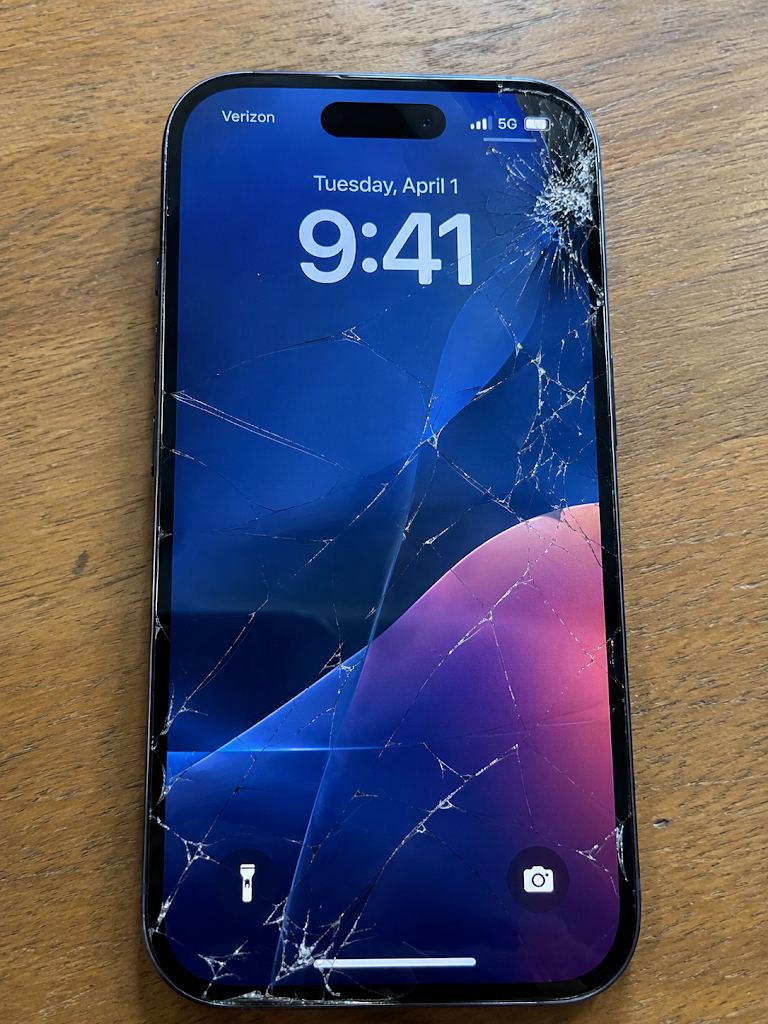 iPhone with a badly cracked screen waiting for a mobile screen repair in Milton